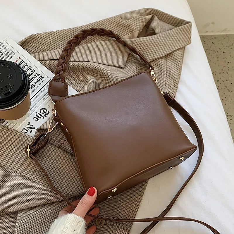 Khaki woven crossbody bucket bag with a buckle, shown on a model for scale
