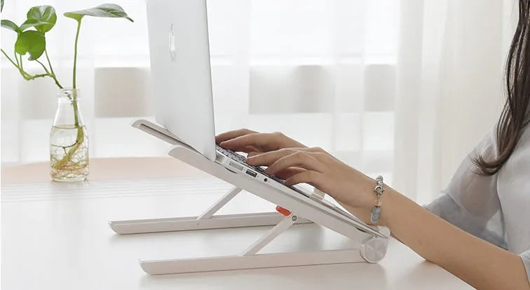 White foldable laptop stand bracket for Apple MacBook on a desktop.