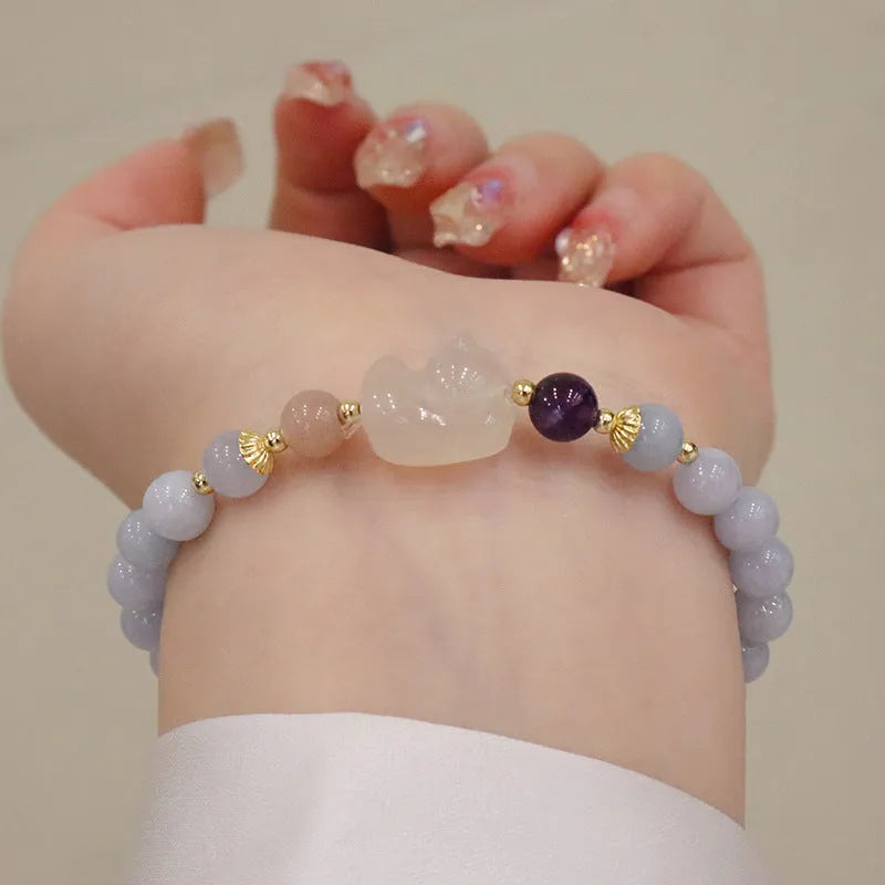 Gold plated bracelet with a detailed artificial crystal charm pendant on a woman's wrist.