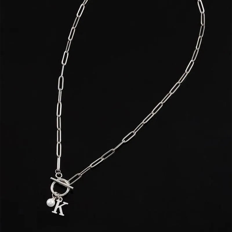 Stainless steel clip chain necklace with raised letter A pendant and imitation pearl in gold colour on a white background