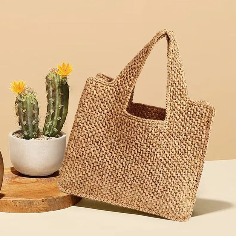 Woven straw bucket tote bag in a neutral colour with double straps and an open outer pocket.