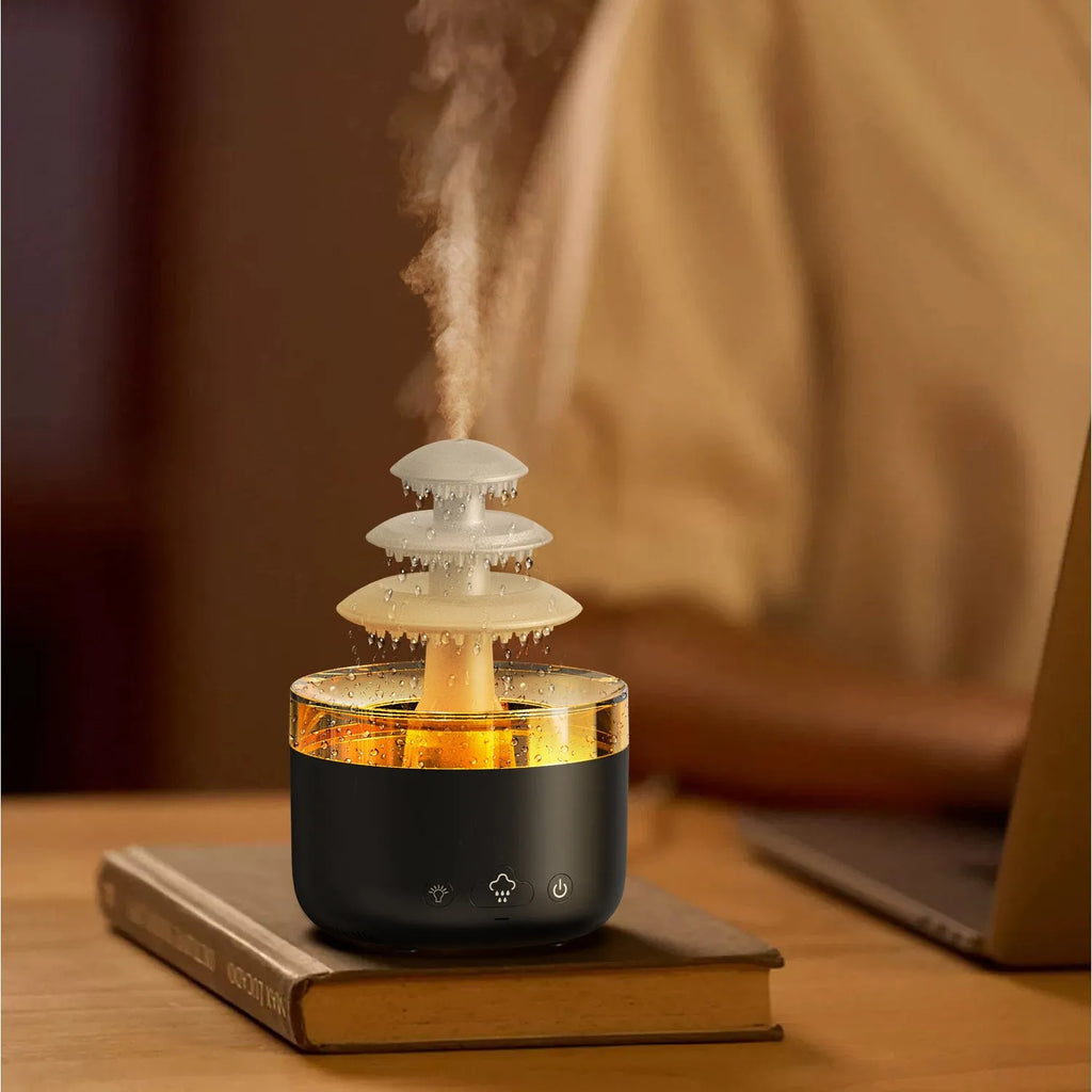 White cloud rain design ultrasonic air humidifier and essential oil diffuser with colourful LED lights on a table.