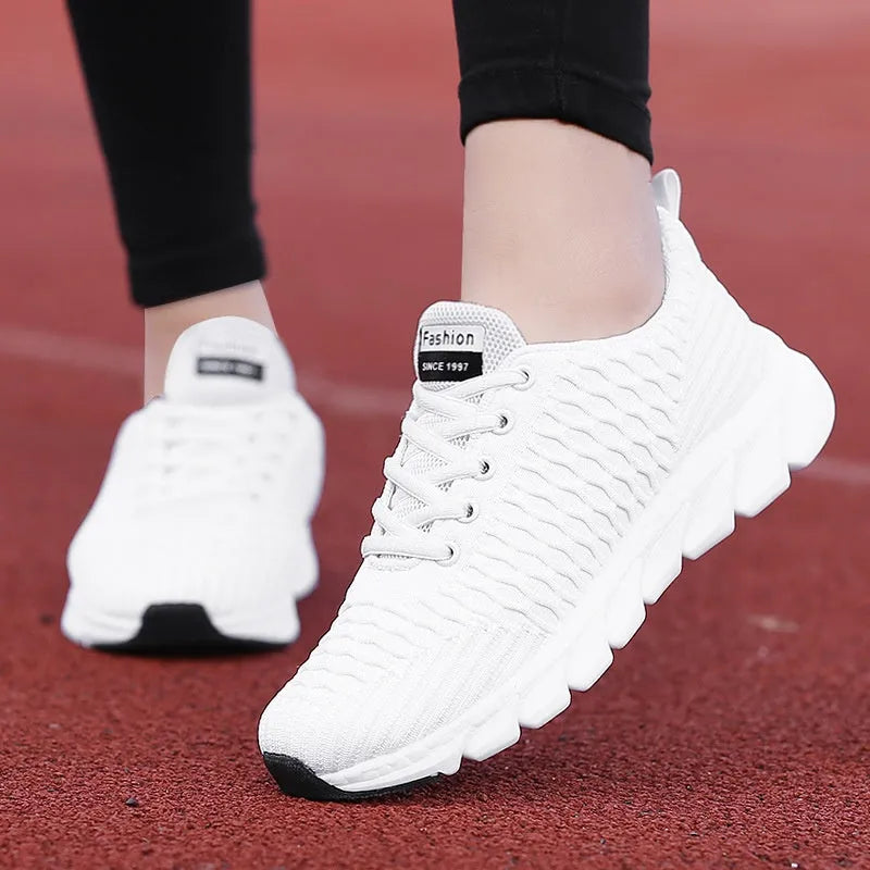 Women's running shoes in black, pink, and white colours showing fly weaving upper and rubber outsole.