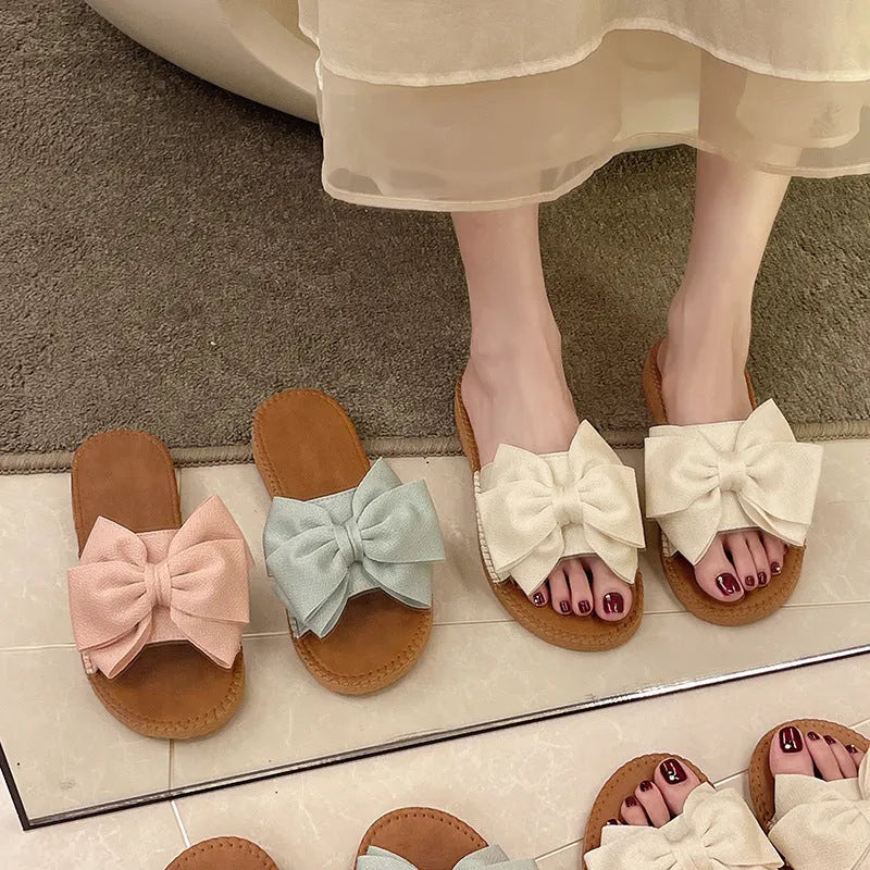 Women's beige suede slip-on sandals with bow detail and rubber sole