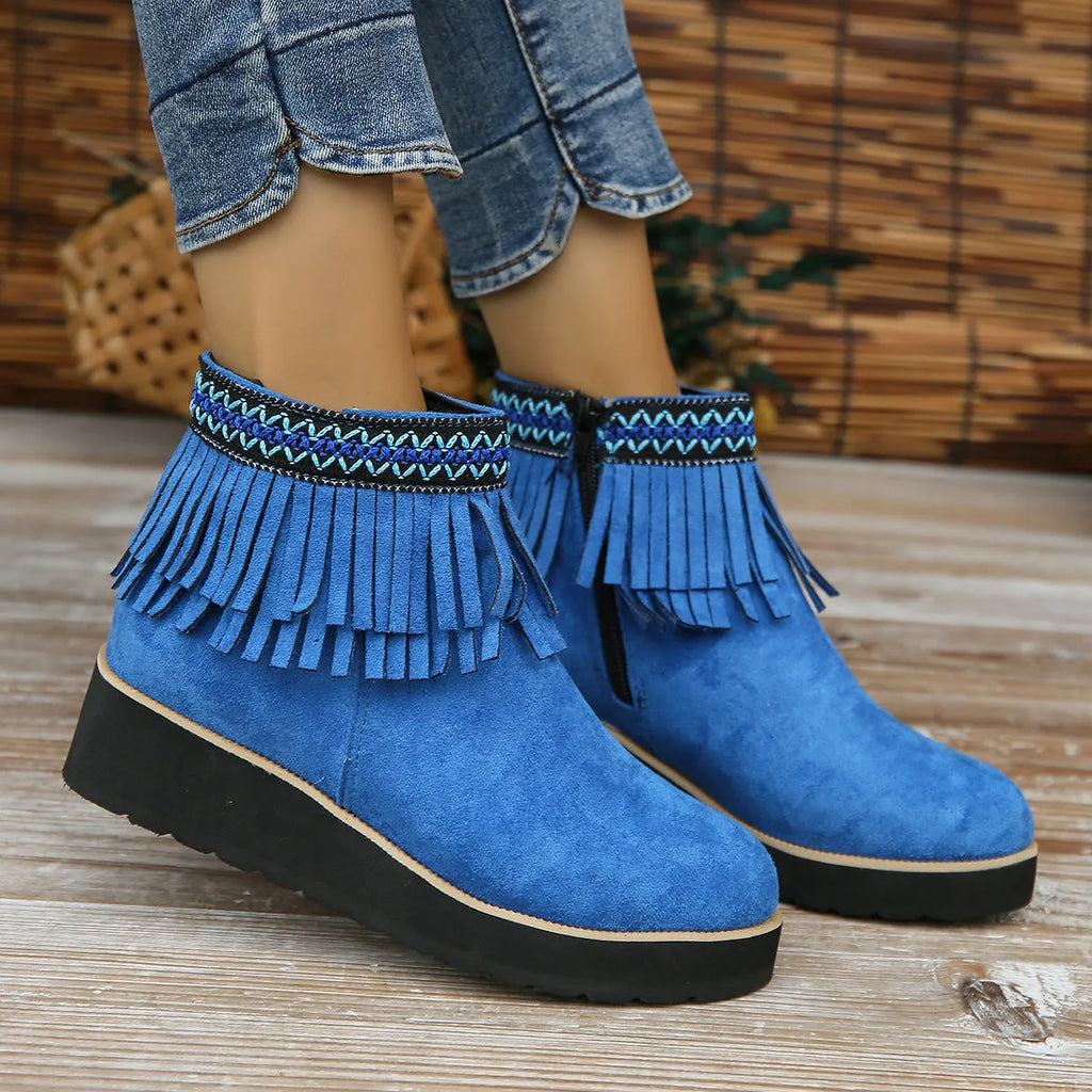 Women's black suede wedge bootie with a thick sole, side zipper, and tassel detail.