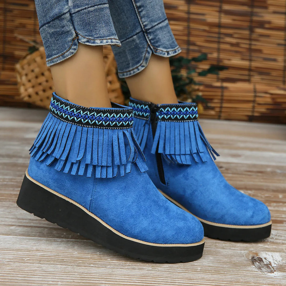 Women's black suede wedge bootie with a thick sole, side zipper, and tassel detail.
