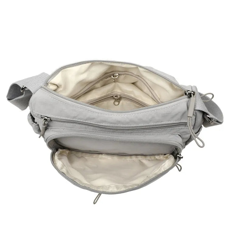 Soft water-repellent nylon crossbody bag with a three-dimensional front pocket and adjustable strap.