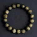 A natural obsidian crater ball bracelet in gold or silver meteorite colour on a wrist, showing textured bead detail.