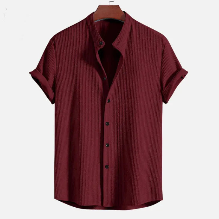 A man's loose-fitting short sleeve casual shirt in a solid colour, made from lightweight polyester fabric.