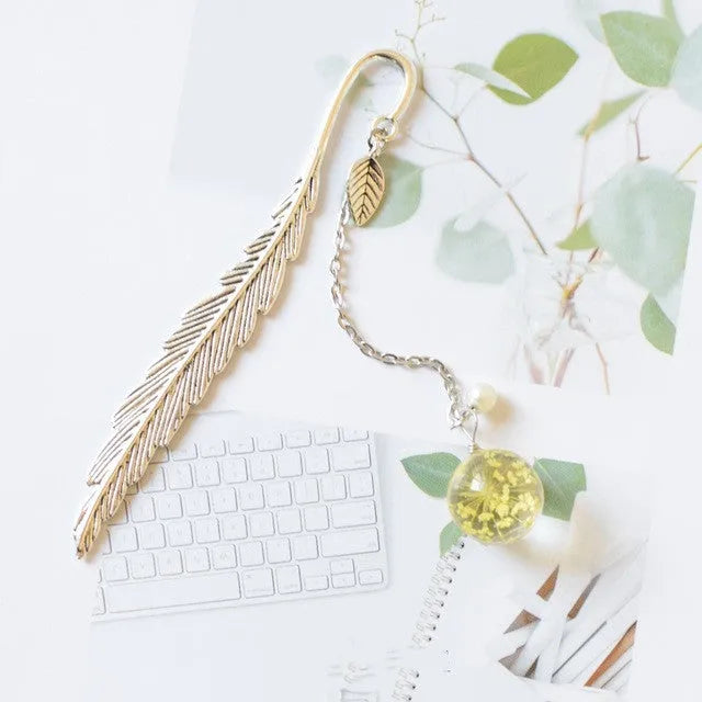Flat metal bookmark with a dried flower inside, showing colour options like blue starry sky and dandelion.
