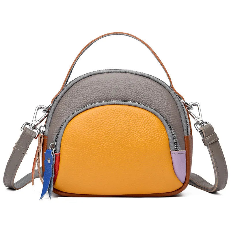 Round hand-held crossbody bag made from first layer cowhide leather with visible sewing line detail on exterior