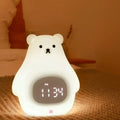 White silicone bear-shaped night light with soft glow, remote control, and button switch on a bedside table.