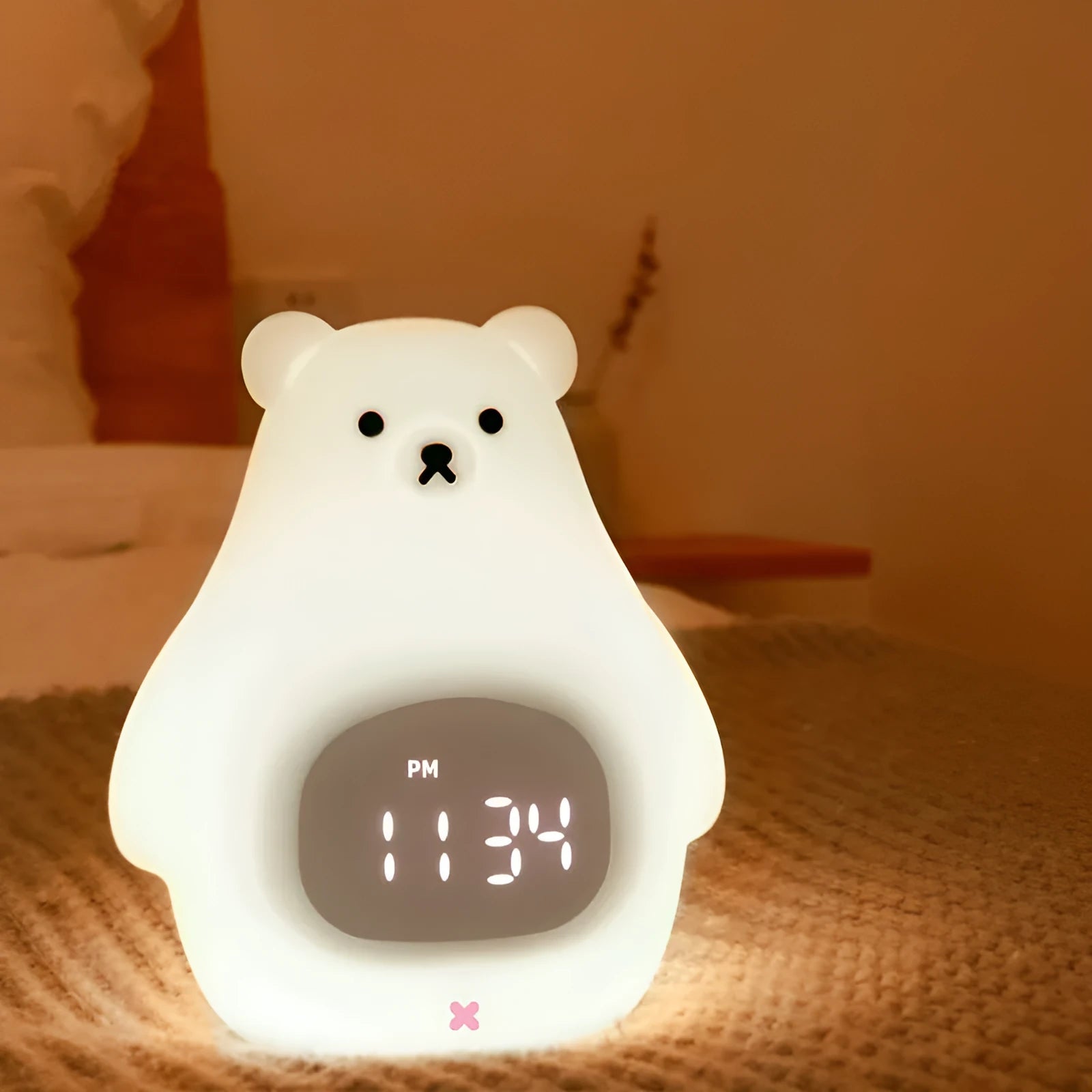 White silicone bear-shaped night light with soft glow, remote control, and button switch on a bedside table.