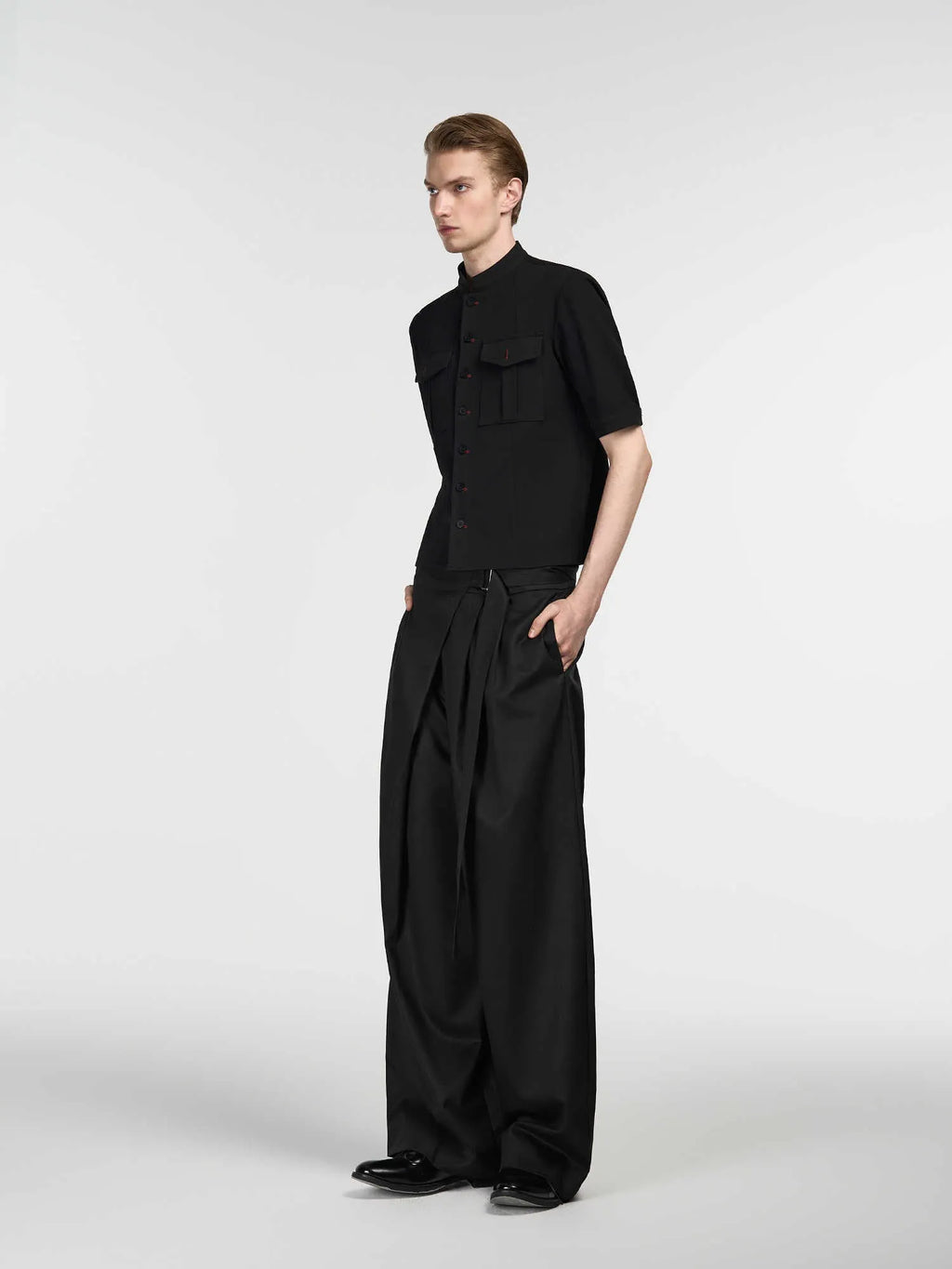 Black straight-leg trousers with a single pleat and adjustable waistband laid flat.