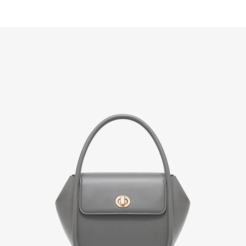 A women's leather wing-shaped tote bag with a metal latch, shown in blue on a cross-body strap.