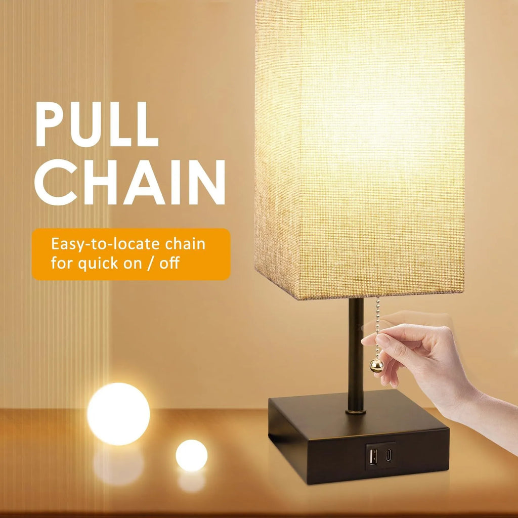 Small bedside table lamp with fabric shade and USB charging ports on a nightstand with pull chain control