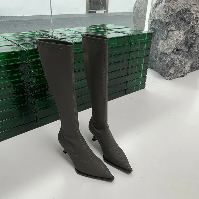 Women's pointed toe knee-high boots in black with a stiletto heel and a visible back zipper closure.