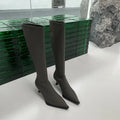 Women's pointed toe knee-high boots in black with a stiletto heel and a visible back zipper closure.
