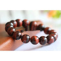 Geometric wood alexandrite bracelet with round beads showing Lightning Cat's Eye effect.