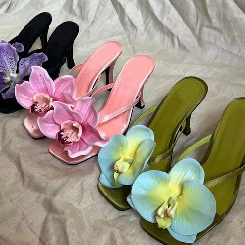 Pink women's sandals with artificial Phalaenopsis flower, satin upper, and mid heel.