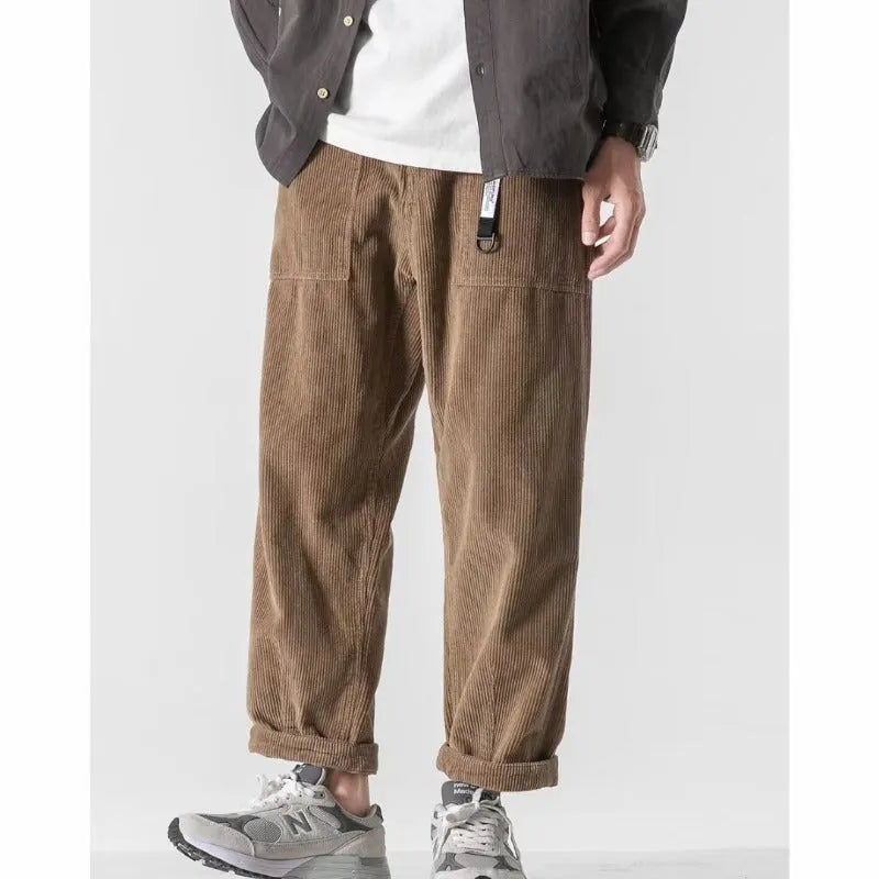 Man wearing loose straight tapered trousers in dark grey, showcasing the straight leg and relaxed fit.
