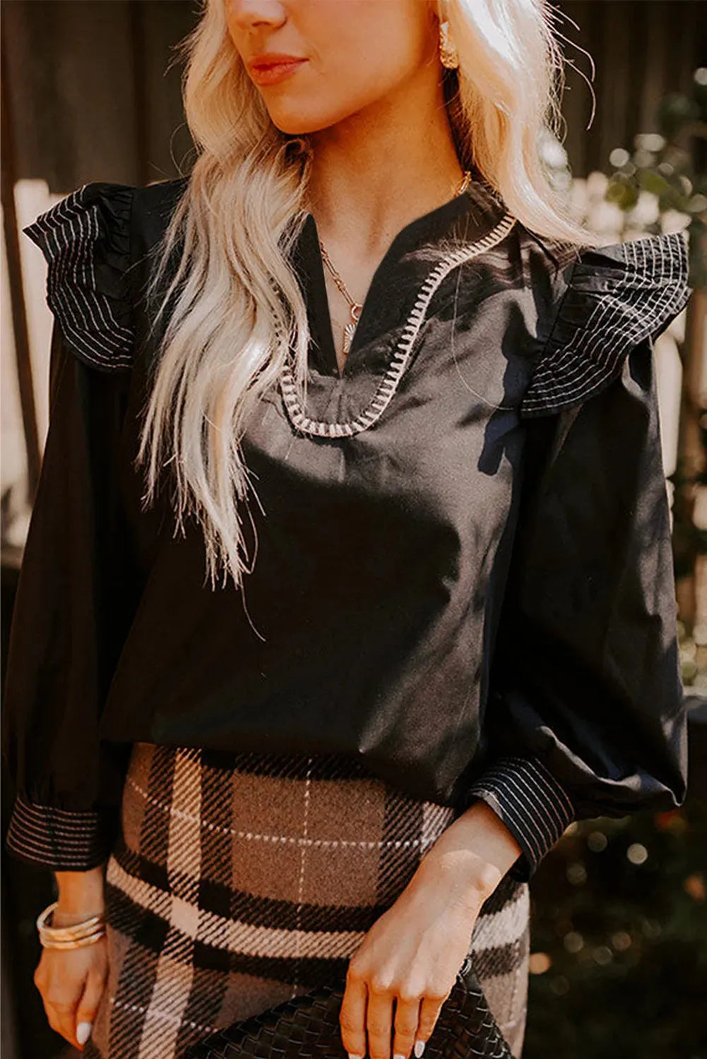 Black women's blouse with V-neck collar, long ruffle sleeves, and contrast colour stitching.