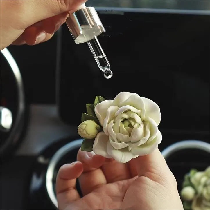 Solid jasmine car perfume diffuser clipped onto a car air vent, showing off white colour.