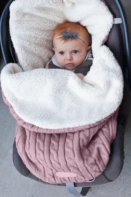 Envelope-style baby stroller sleeping bag in beige colour with thick filling, shown next to a pram.