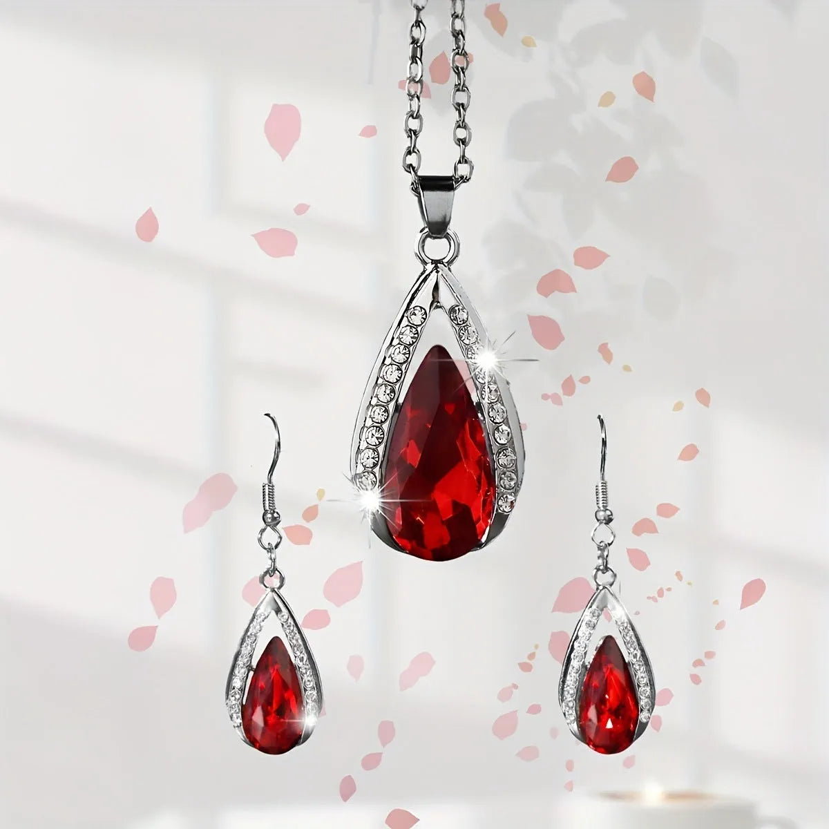 Black and red teardrop-shaped glass pendant necklace and matching stud earrings set on a grey background.