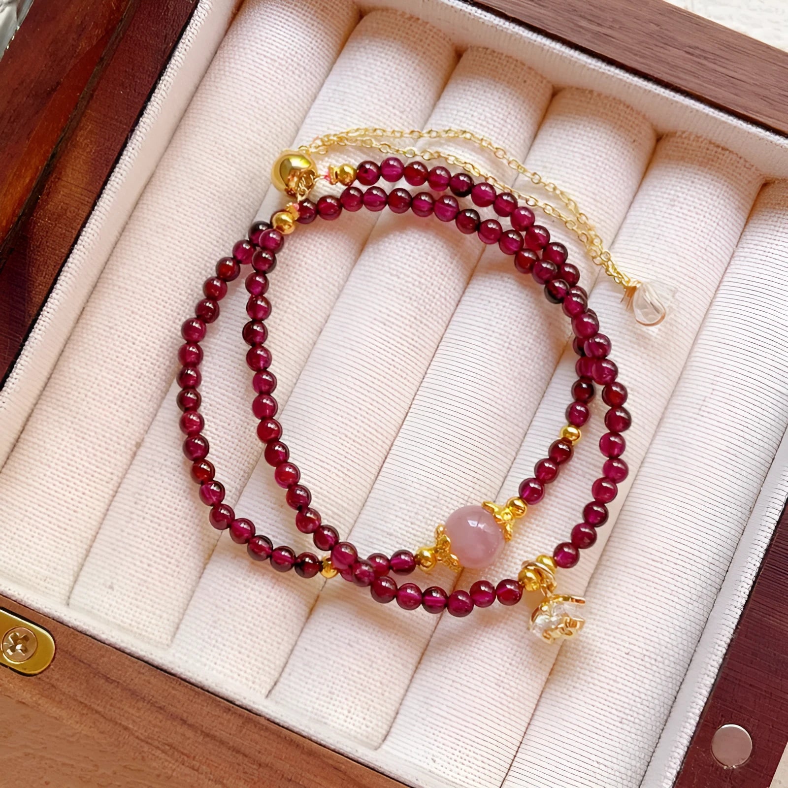 Close-up of a women's double ring bracelet made with natural garnet stones in H311 colour.