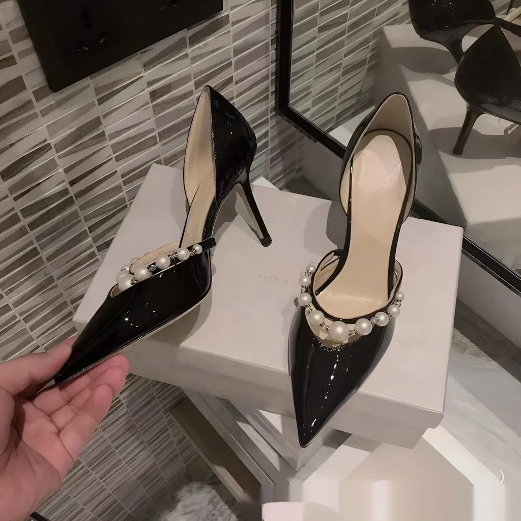 Women's nude pointed toe patent leather stiletto high heel with a pearl decoration on the side.