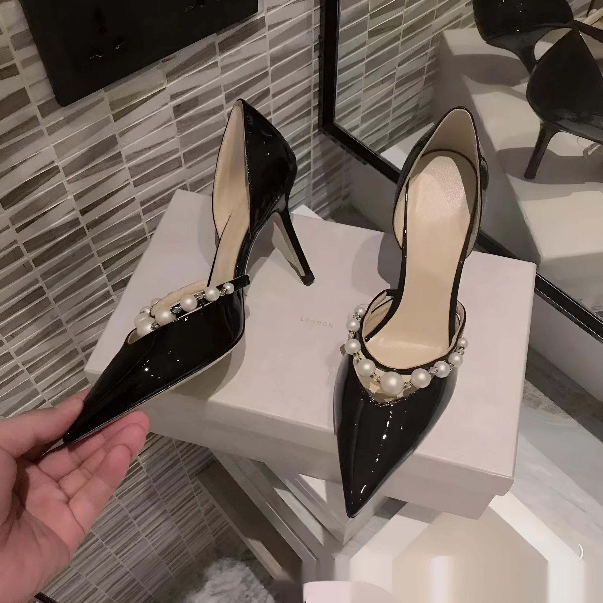 Women's nude pointed toe patent leather stiletto high heel with a pearl decoration on the side.