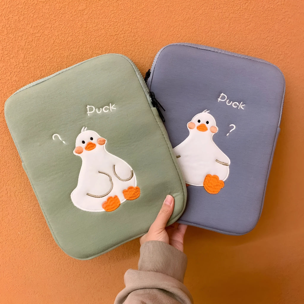 Blue cotton tablet case with embroidered cartoon duck design and a zipper closure, shown next to a green version.