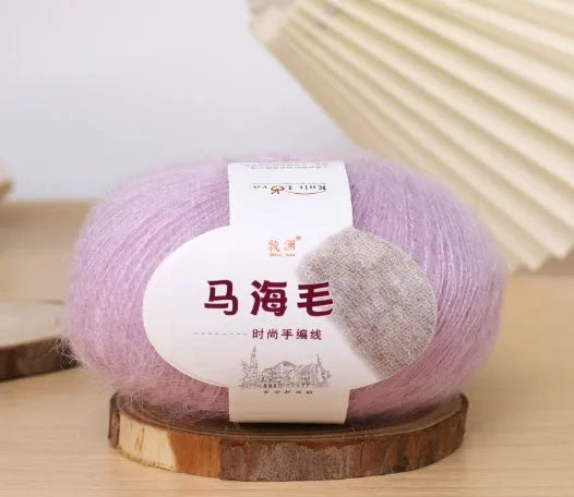 A ball of mohair yarn in a selected colour next to a hand-woven scarf example, showcasing the DIY kit.