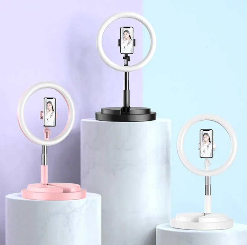 Portable 290mm LED selfie ring light in black on table, showing centre phone holder and adjustable brightness button