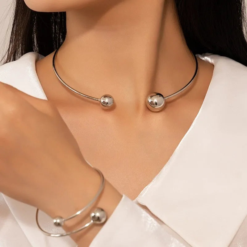 Gold silver ball dislocation thin open-end bangle bracelet with matching necklace ornament on white background
