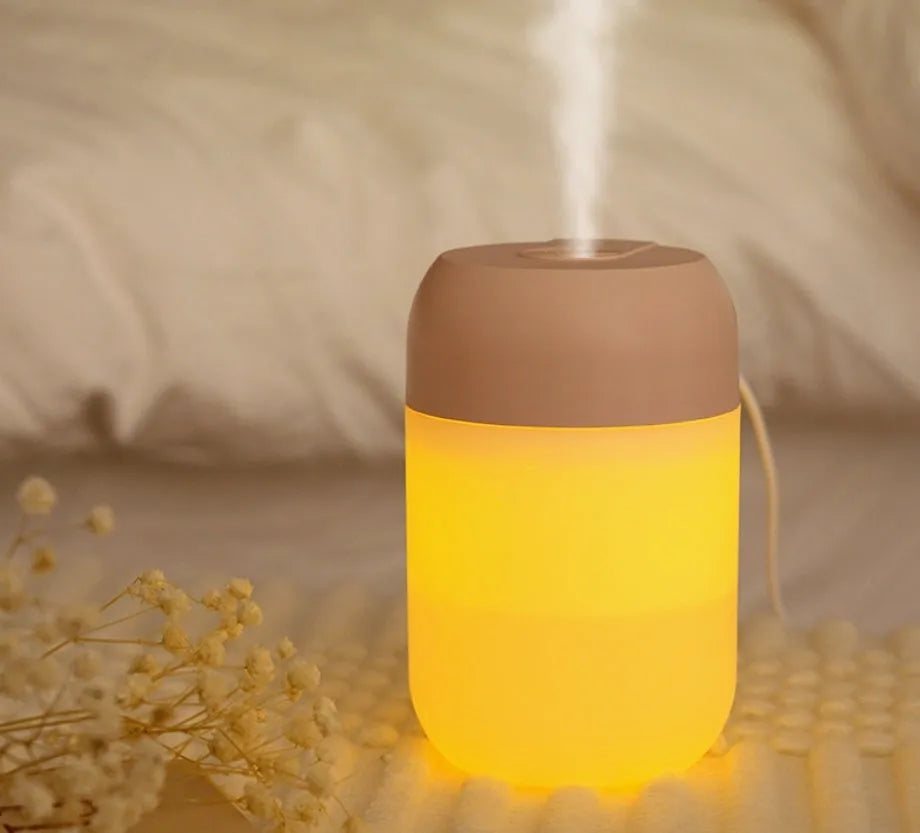 White cylindrical mini USB humidifier on a wooden desk next to a laptop.