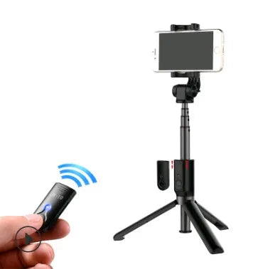 Black Bluetooth selfie stick with tripod base and remote control extended next to smartphone