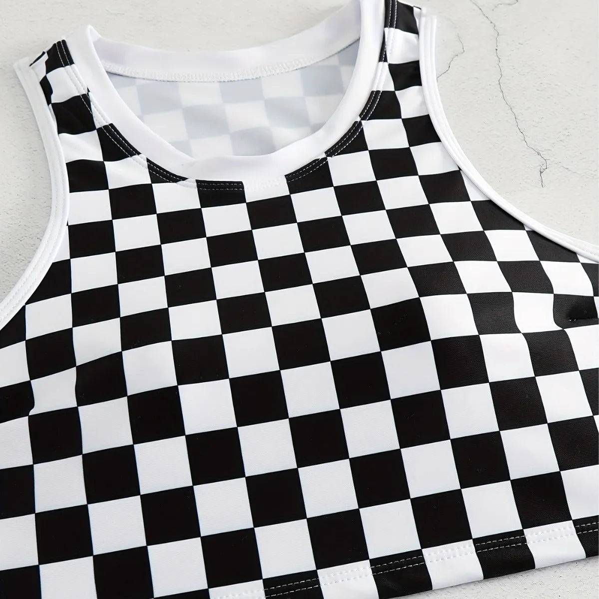 Women's backless racing swimsuit with shoulder suspender strap in black and white chessboard pattern