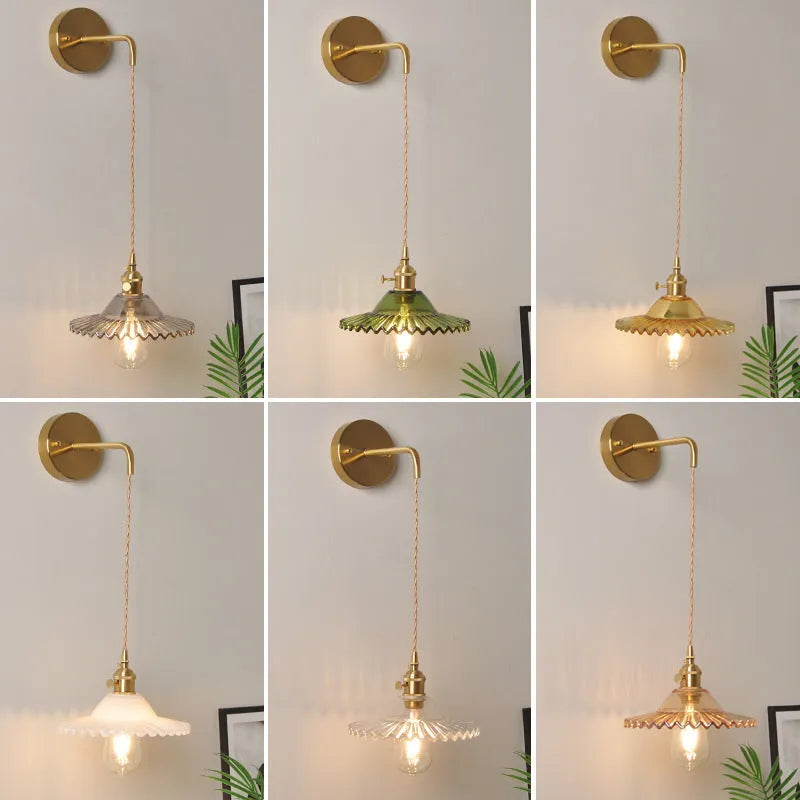 Brass wall lamp with an adjustable smoked grey glass lotus shade mounted beside a bed.