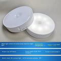 Small round beige and white LED motion sensor night light with USB charging cable and adhesive tape.