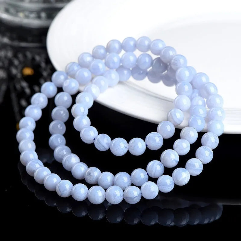 Blue agate bead bracelet with striped patterns and a Ruyi charm on a white background.