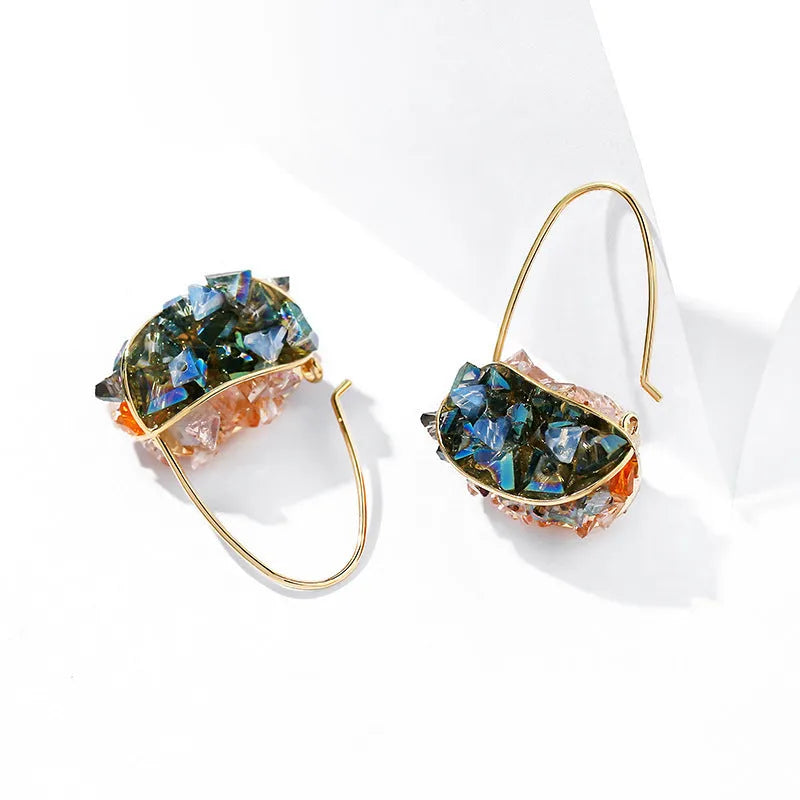 Pair of champagne gold geometric quadrilateral drop earrings on a neutral background