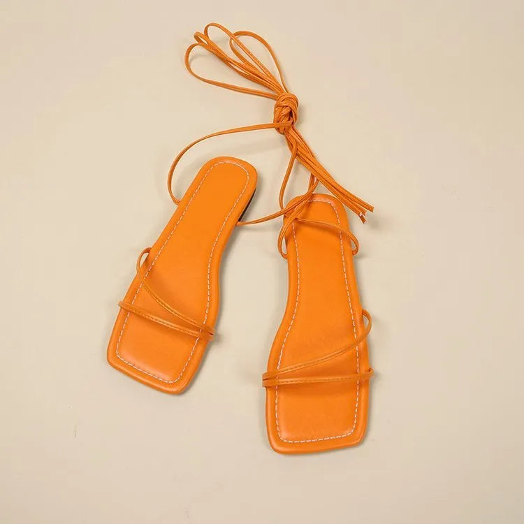 Women's flat sandals with ankle bandage straps and front lace-up in white, black, or orange.