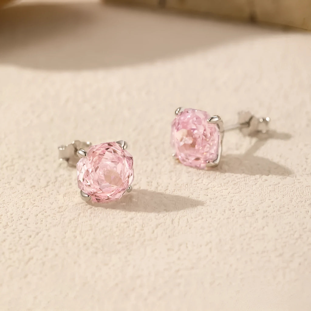 Close-up of S925 sterling silver rose stud earrings for women on a pink background.