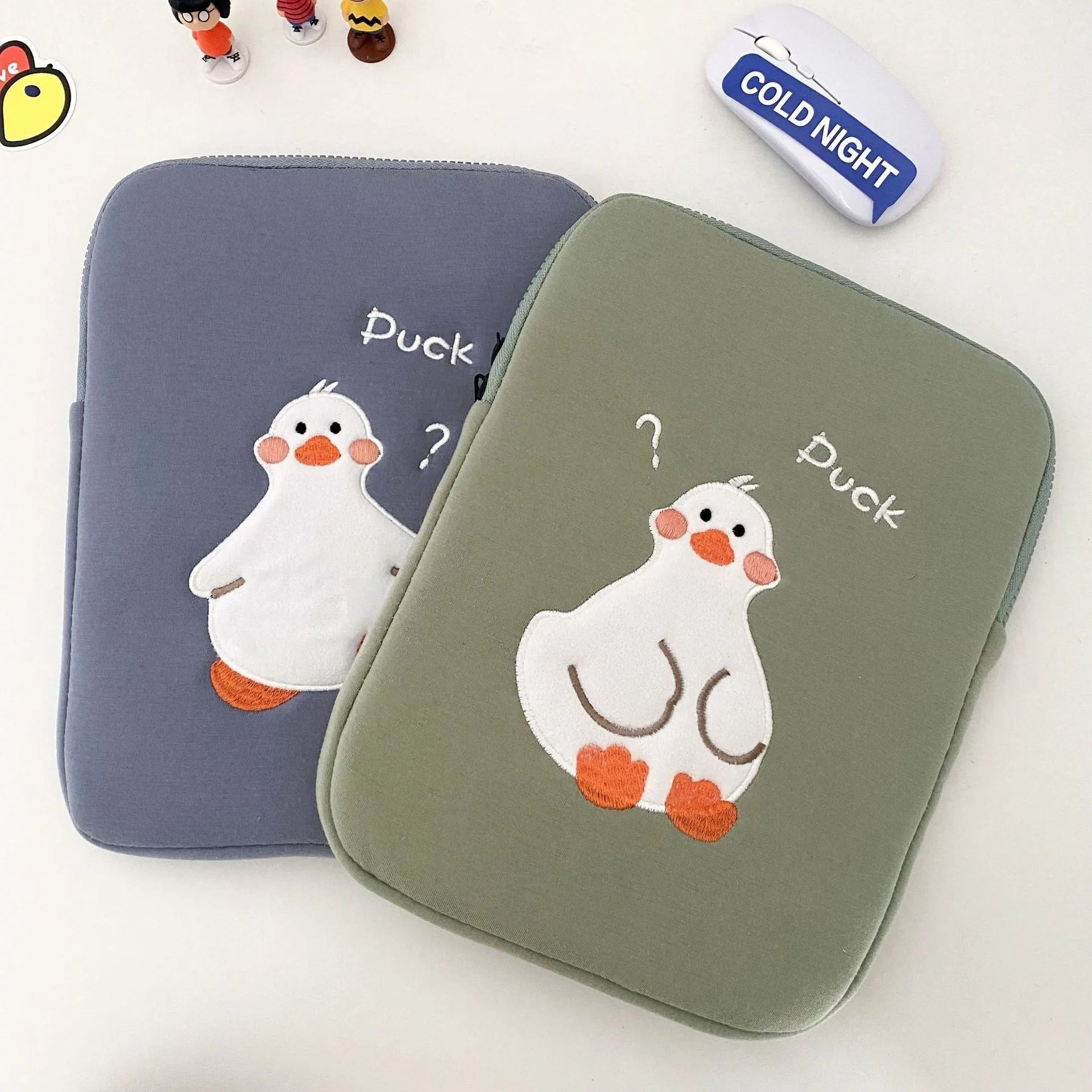 Blue cotton tablet case with embroidered cartoon duck design and a zipper closure, shown next to a green version.