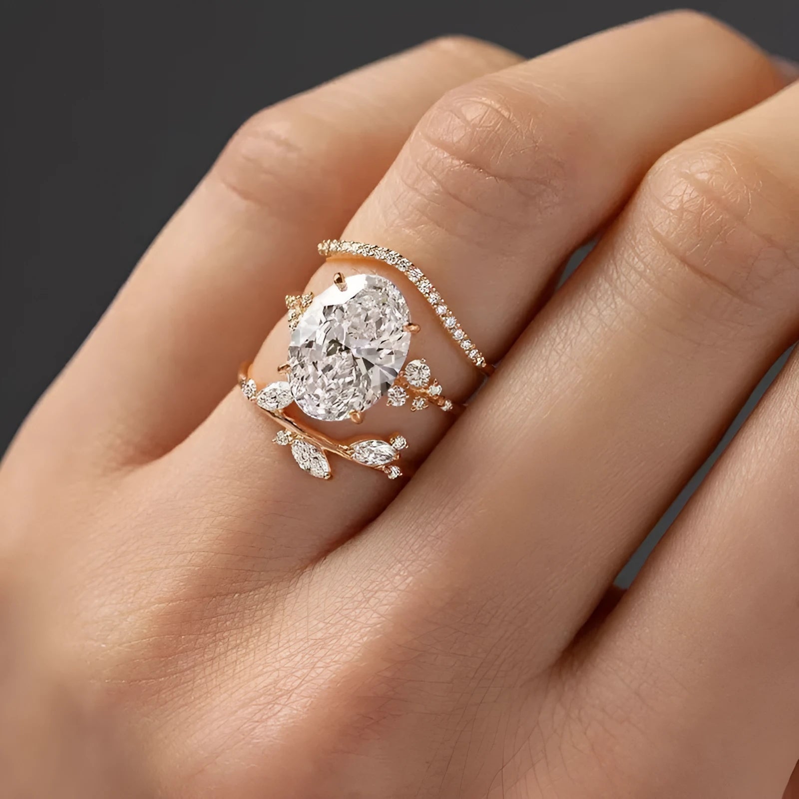 Copper zircon ring set with goose egg-shaped cut in Q681 gold on hand, three rings with flower and geometry shapes