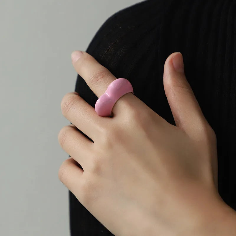 Heart-shaped zinc alloy ring with three-dimensional enamel colour in black, pink, purple, or red on a finger.