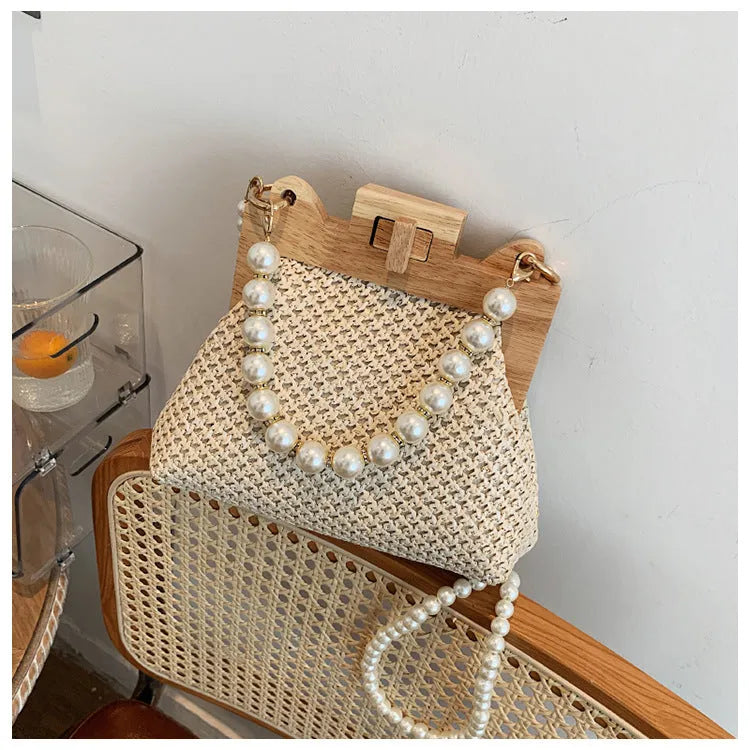 Women's woven straw shoulder bag with pearl chain strap showing internal organisation compartments