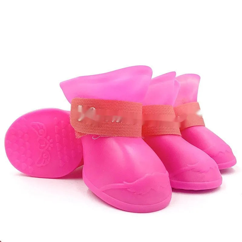 A set of four colourful rubber rain shoes for dogs, showing soft soles and bright pink, blue, orange, and red colours.